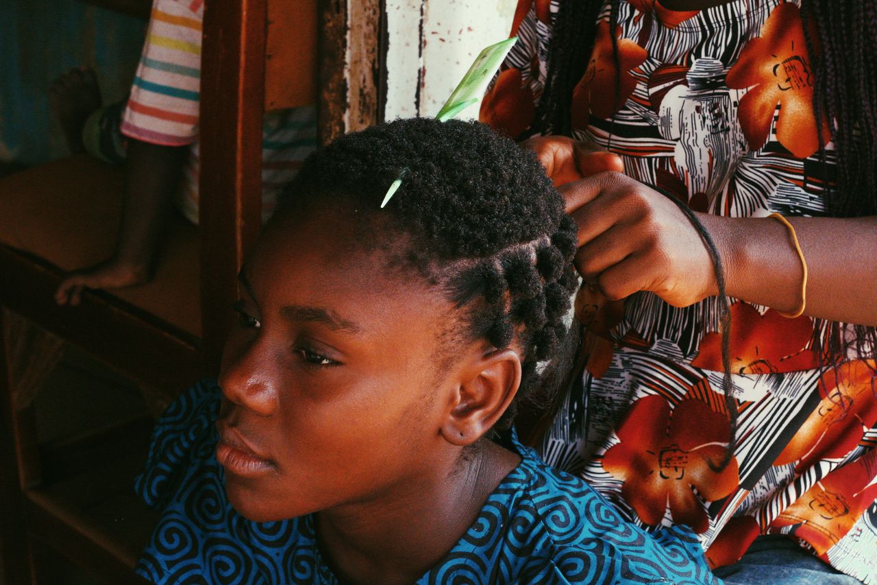 Home A young African girl getting her hair styled, captured in Abuja, Nigeria.