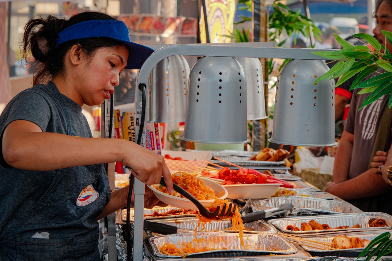 Menu A woman serving vibrant street food at an outdoor market in Toronto, capturing urban culinary culture.